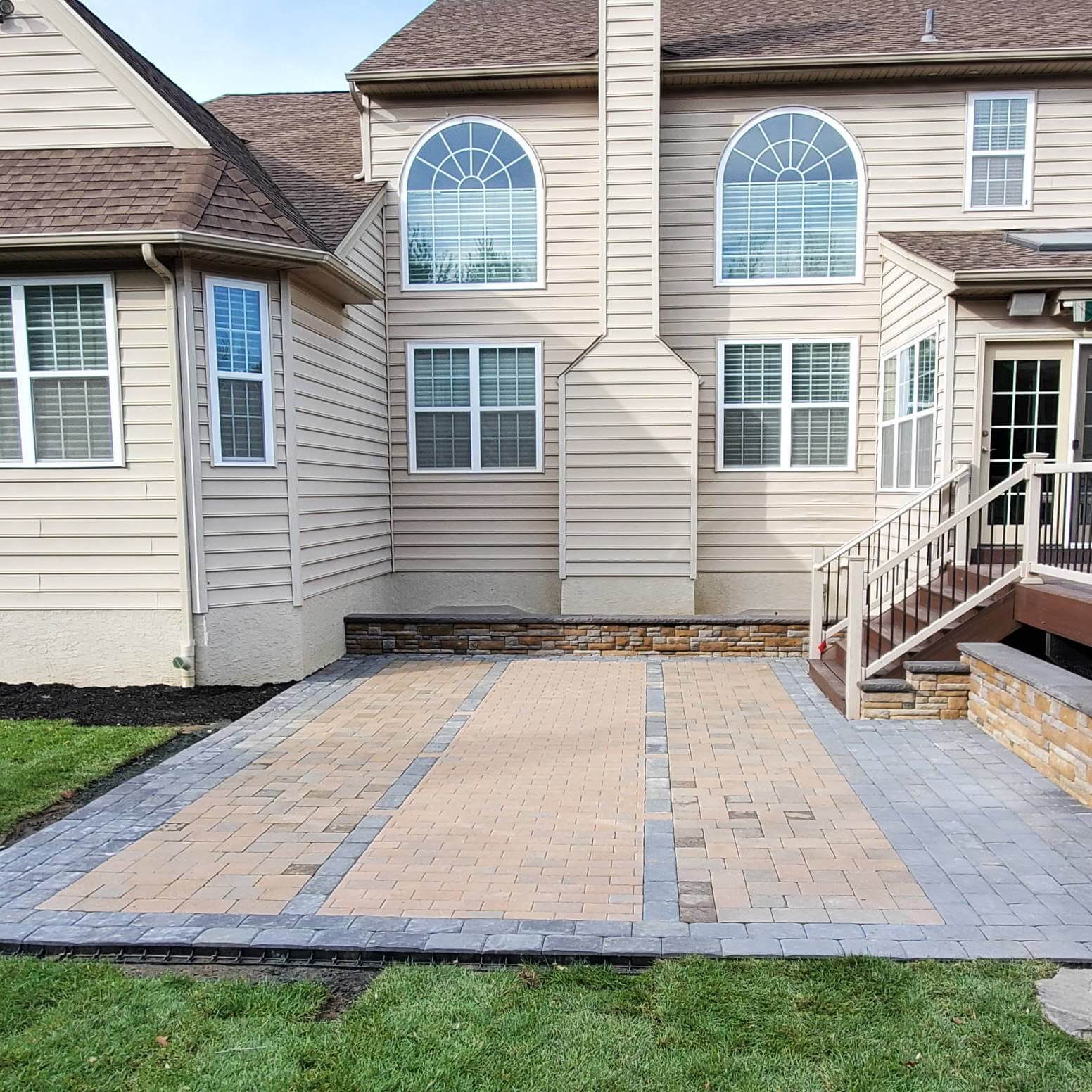 A grey and red hardscaped patio in the backyard of a Delaware home