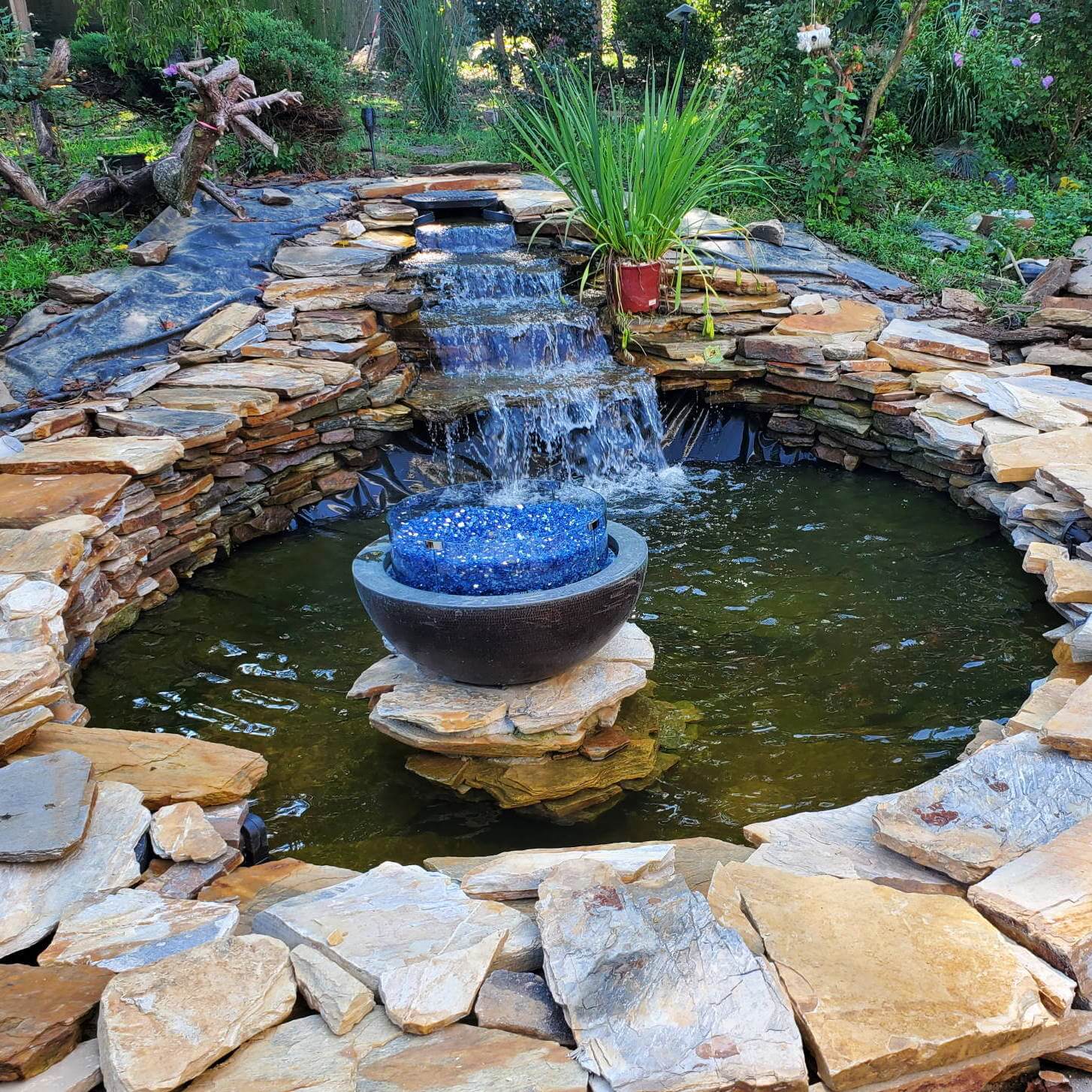 A backyard water fountain lined with stone walls